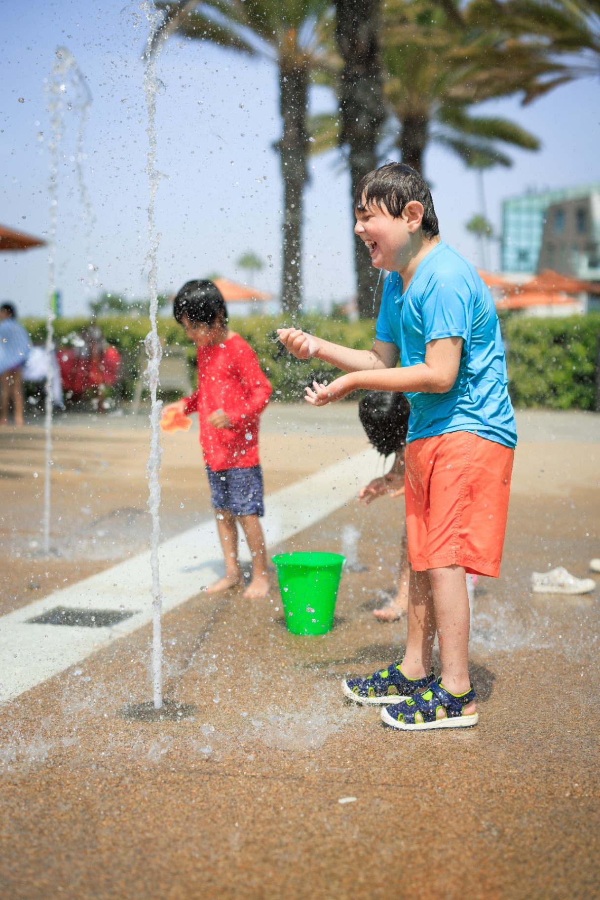 Children laughing and playing together at a sunny outdoor splash pad