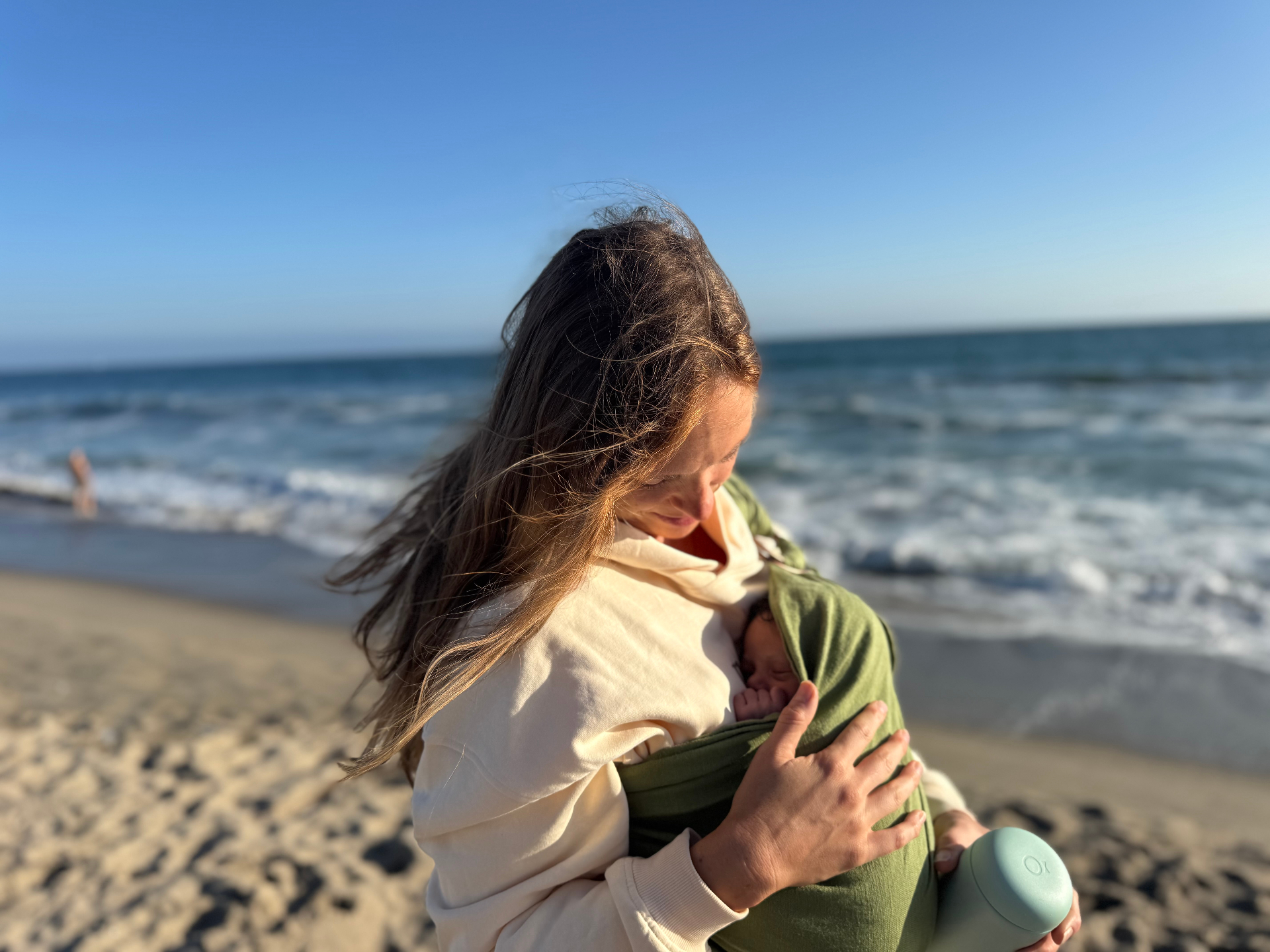 A mother gently feeding her infant a bottle in a sunlit California home